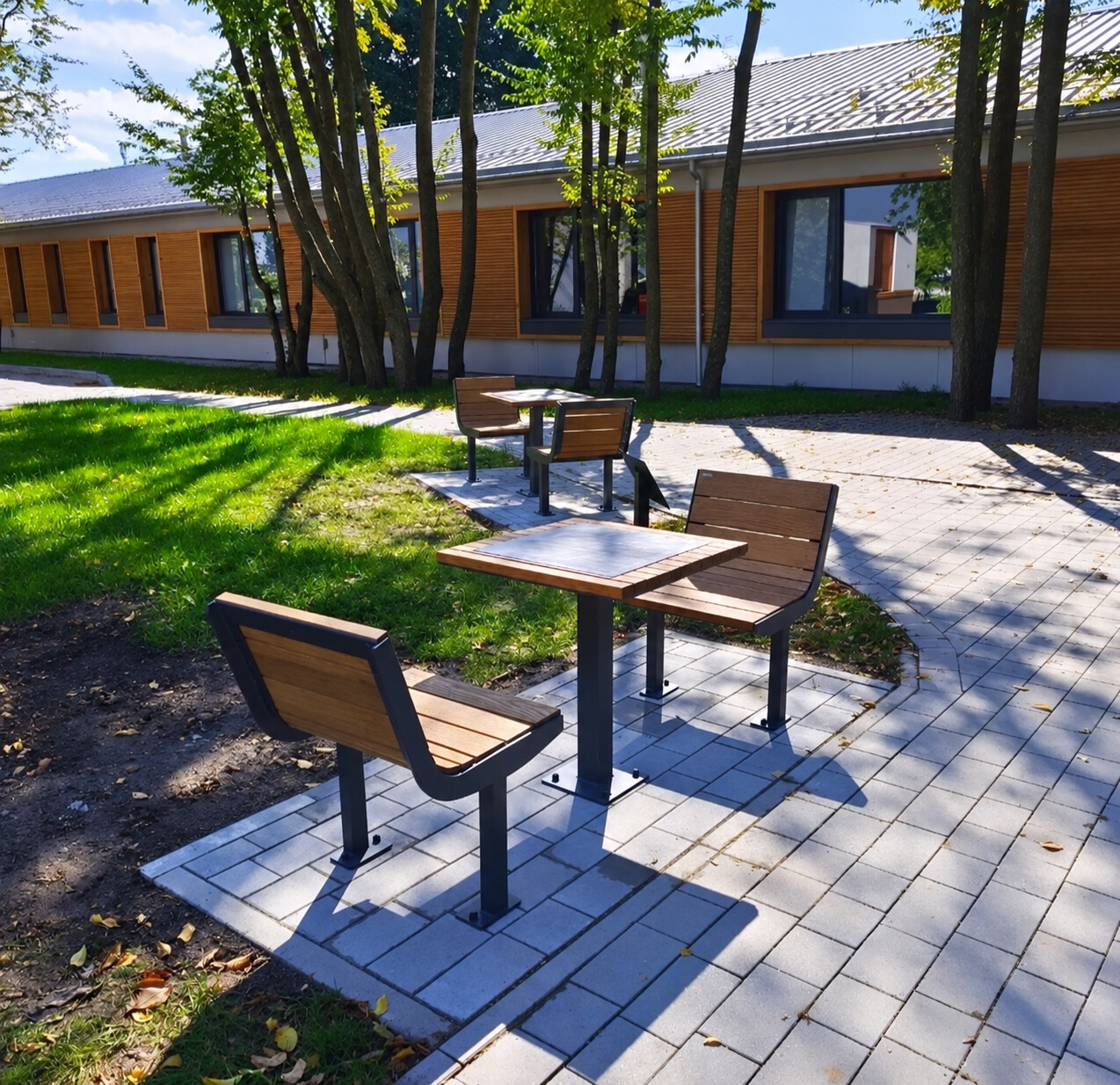 Outdoor tables and seating in a landscaped courtyard at UNBROKEN.