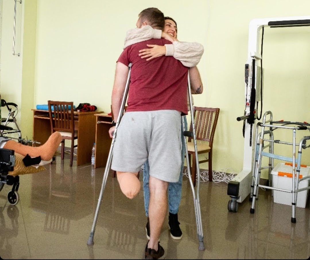 A veteran walking with support while being embraced in a rehabilitation space
