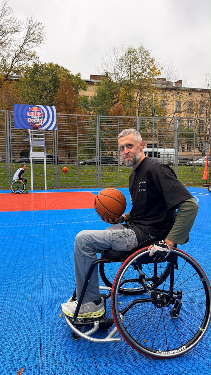 A wheelchair basketball player holding a ball on an outdoor court