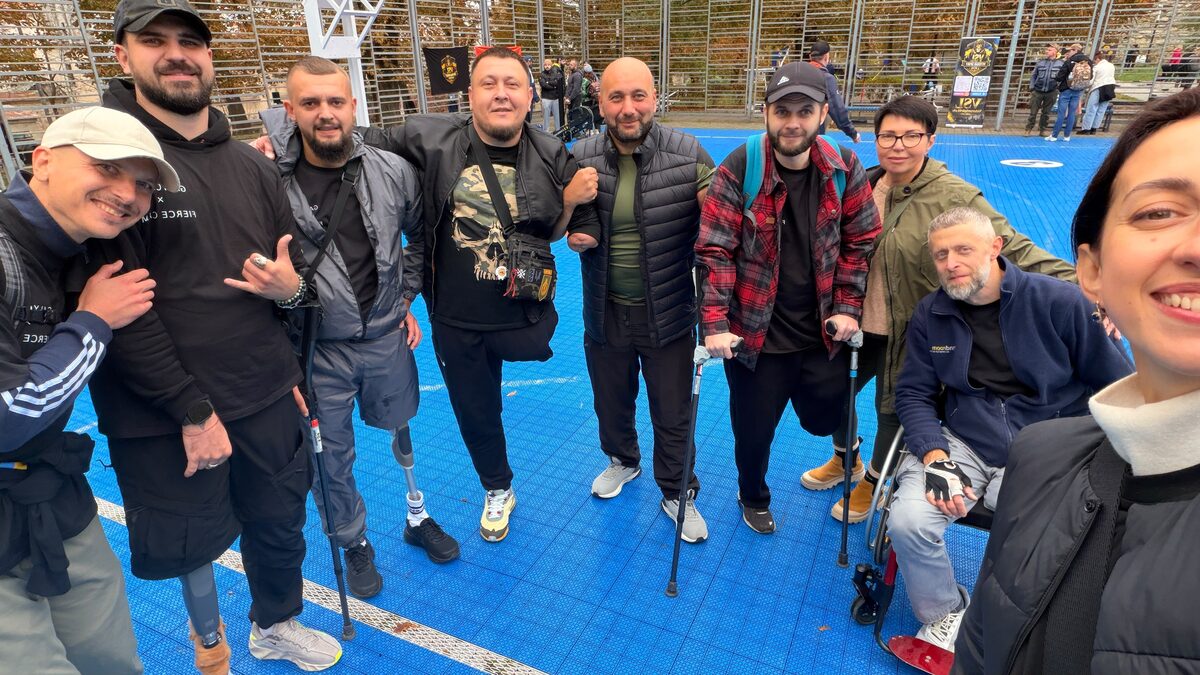Players and supporters gathered together on an outdoor wheelchair basketball court